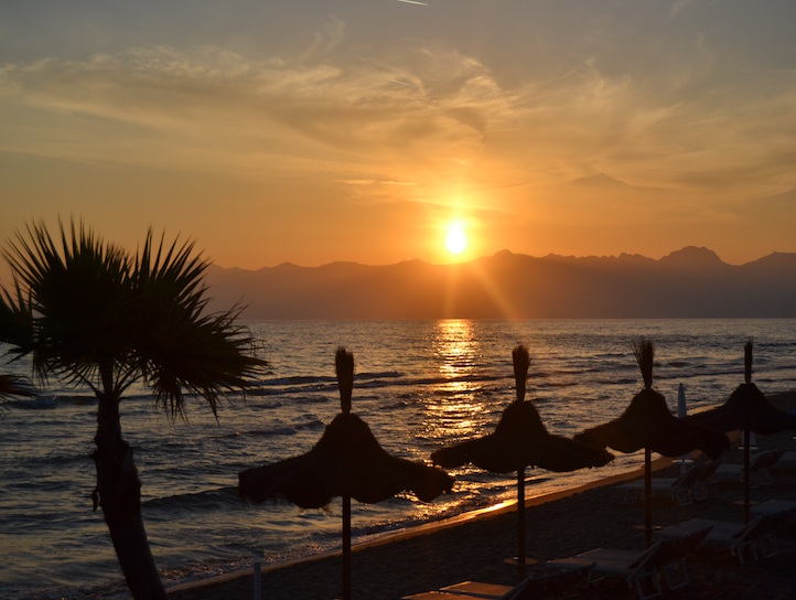 tramonto con ombrelloni di paglia e palma